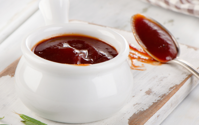 bbq sauce in a white bowl with a spoon on the right side